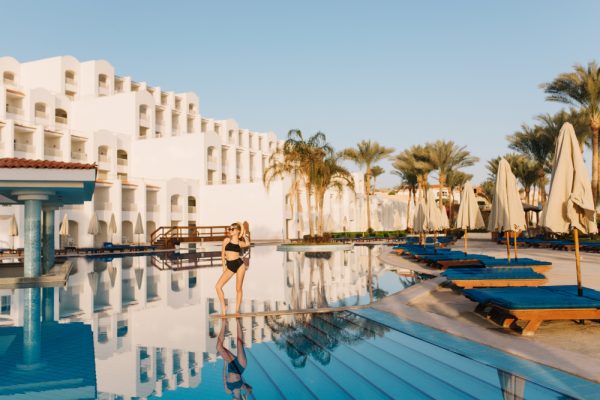hotel-lujo-egipto-estilo-oriental-complejo-bonita-piscina-grande-chica-guapa-modelo-traje-bano-negro-posando-medio-piscina-vacaciones-vacaciones-verano